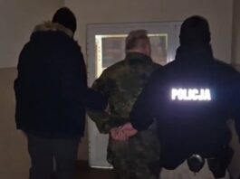 Na zdjęciu dwóch policjantów przetrzymuje w kajdankach zatrzymanego mężczyznę